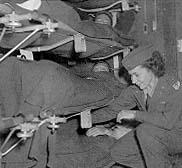 Flight nurse attends a wounded soldier being evacuated by air from the 57th Field Hospital in Prestwick, Scotland, 1944.
